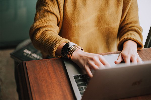 Mid shot of a woman typing at a laptop