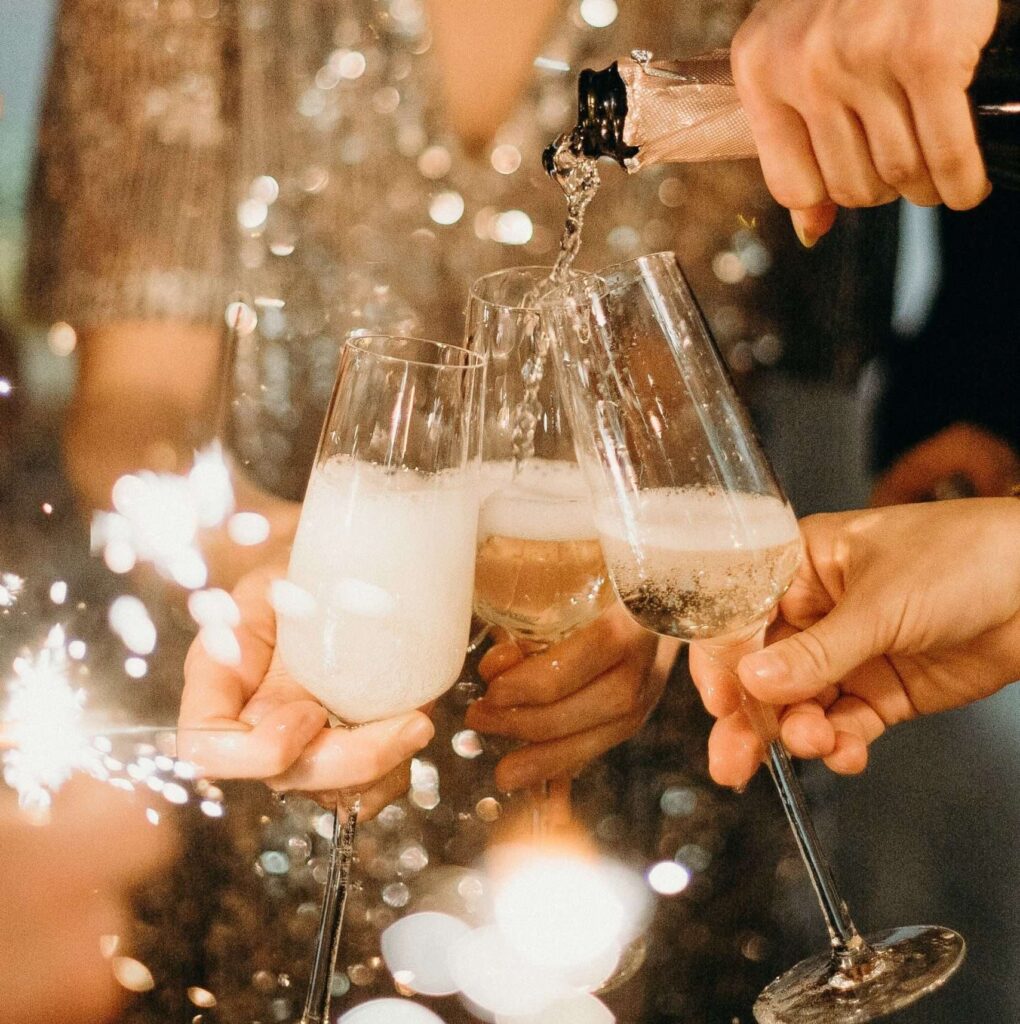 Closeup of champagne pouring into several champagne flutes with a blurry sparkly effect applied