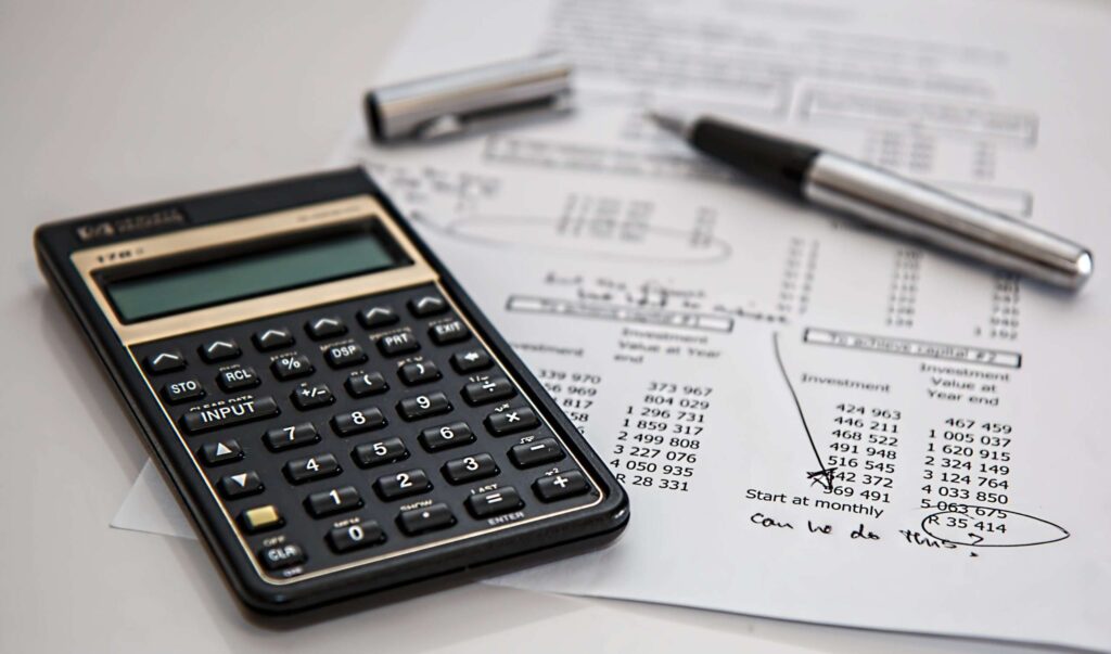 close up of calculator and printout of figures with notes and annotations drawn on with pen