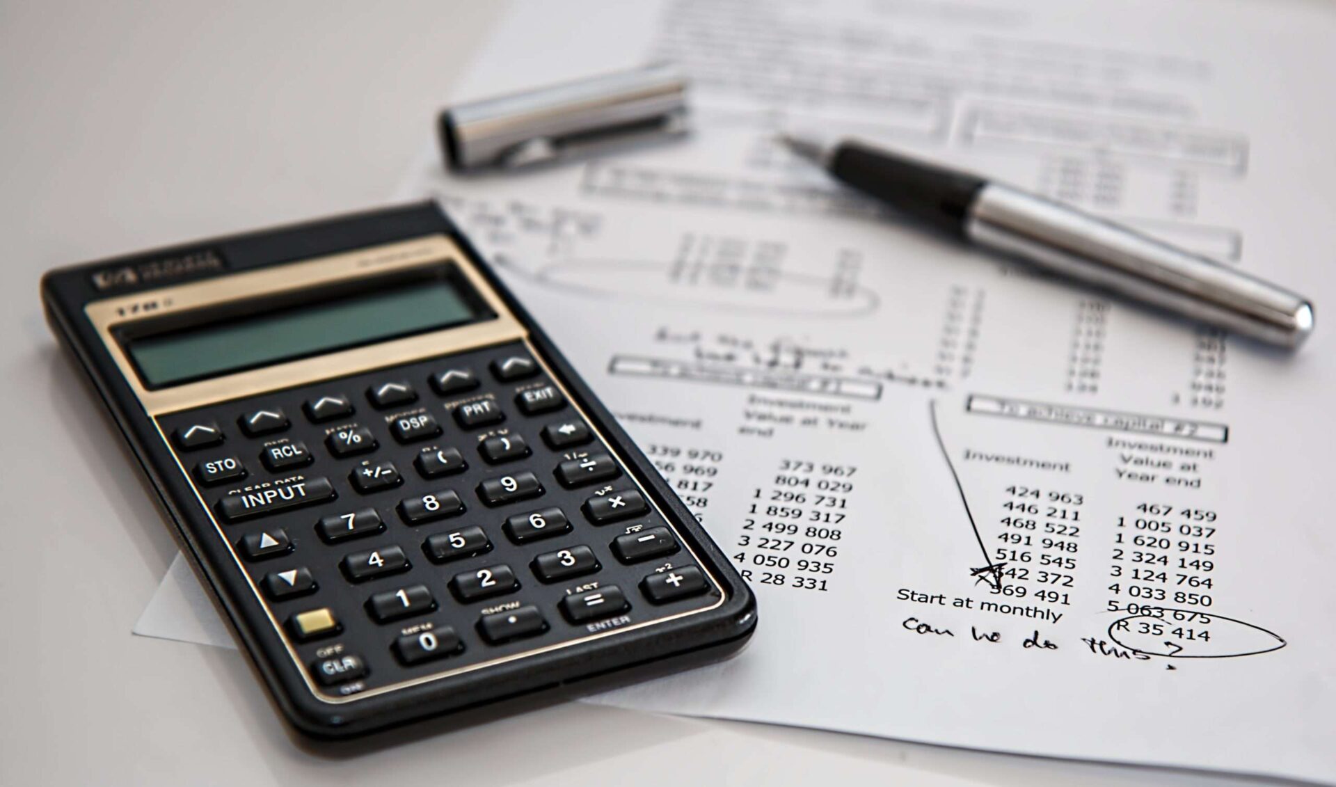 close up of calculator and printout of figures with notes and annotations drawn on with pen
