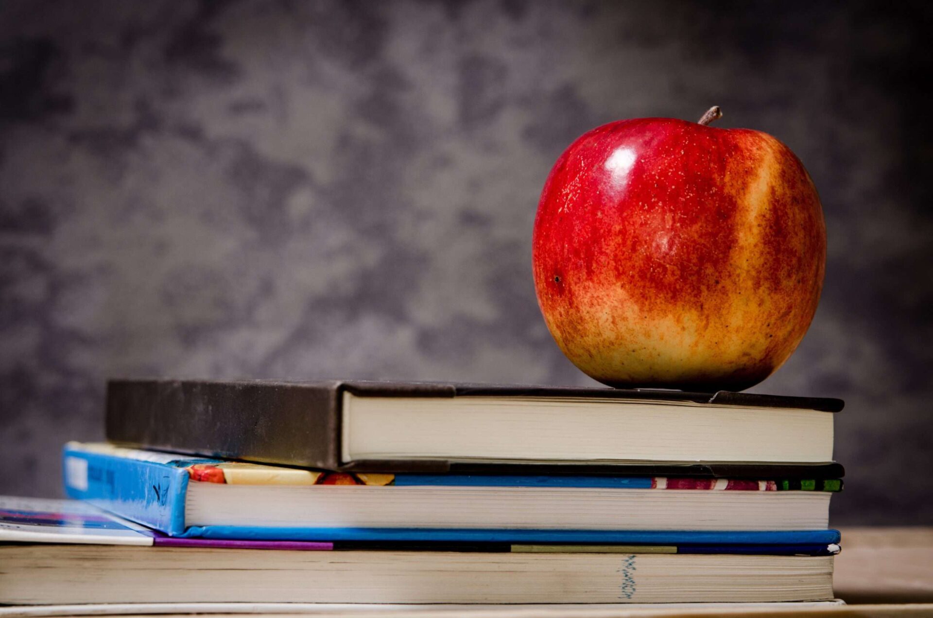 close up of red apple on top of two hardback books