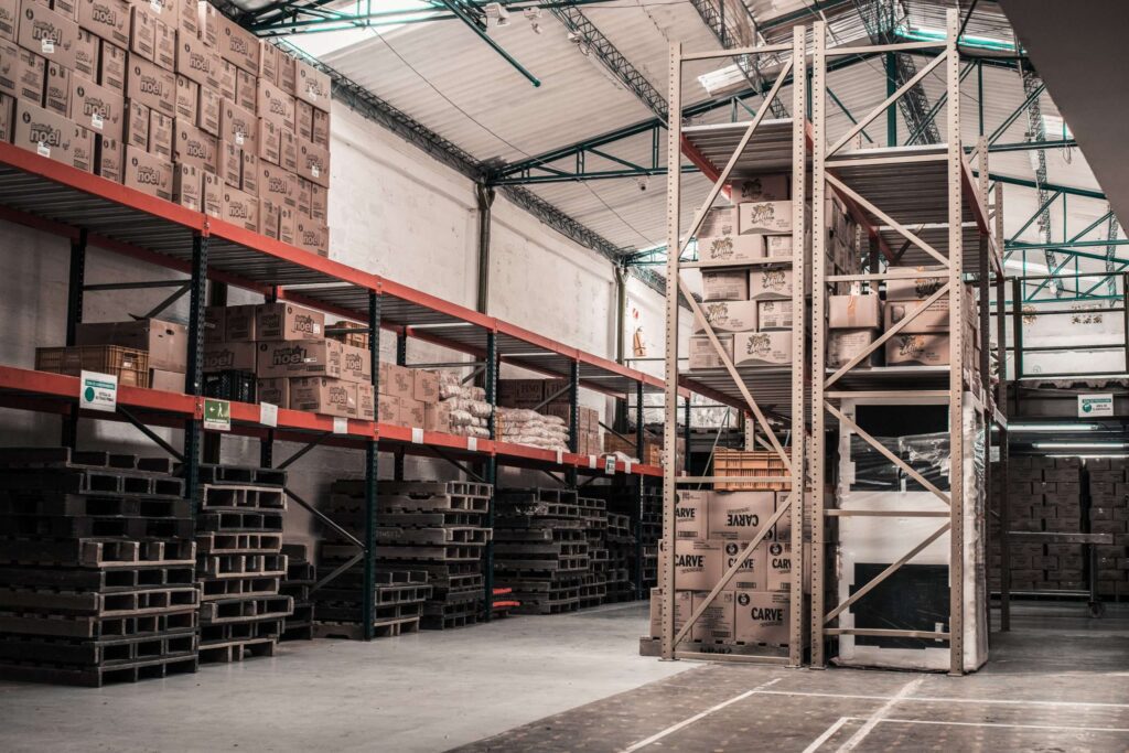 inside of warehouse with metal shelving and pallets of wood and boxes