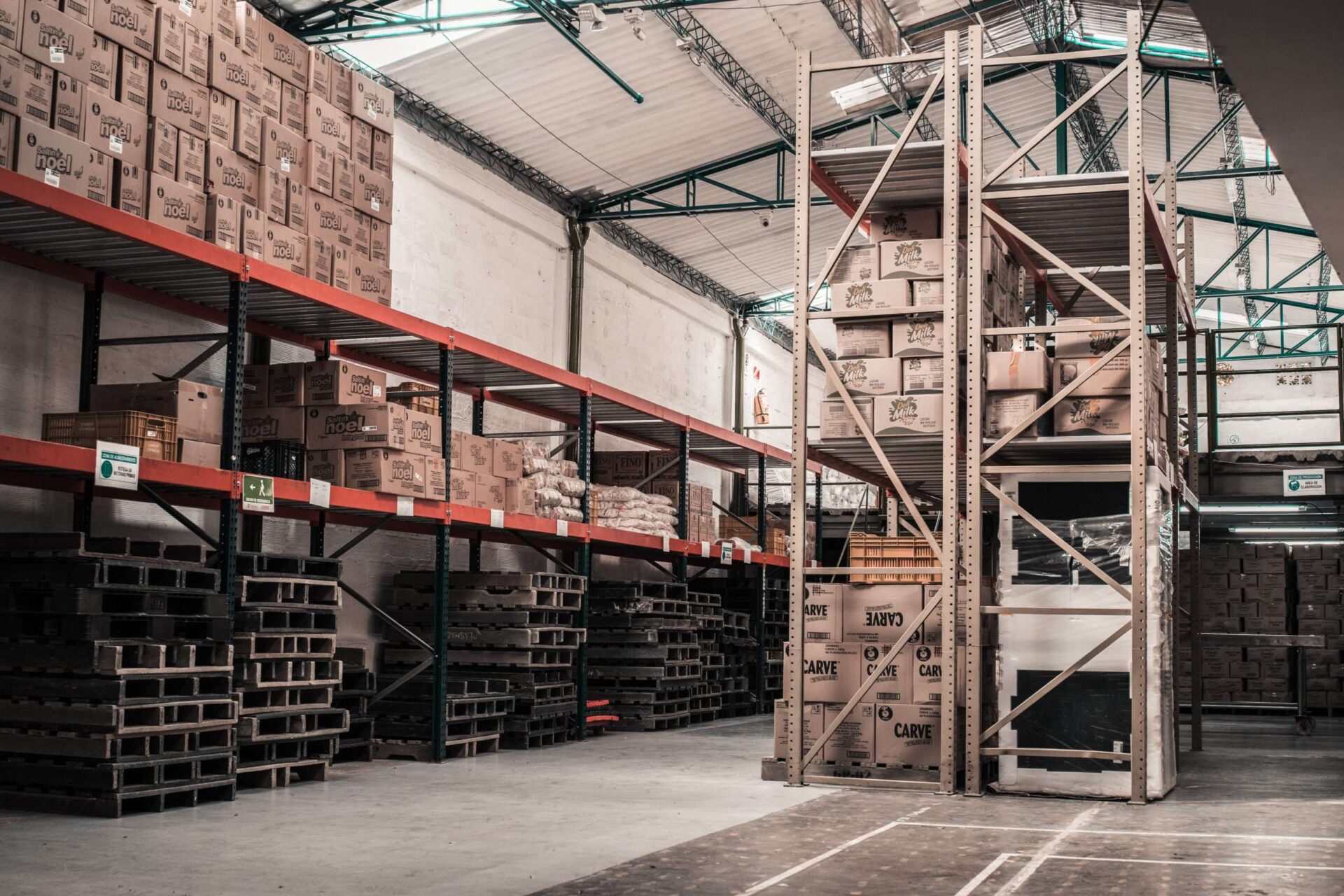 inside of warehouse with metal shelving and pallets of wood and boxes