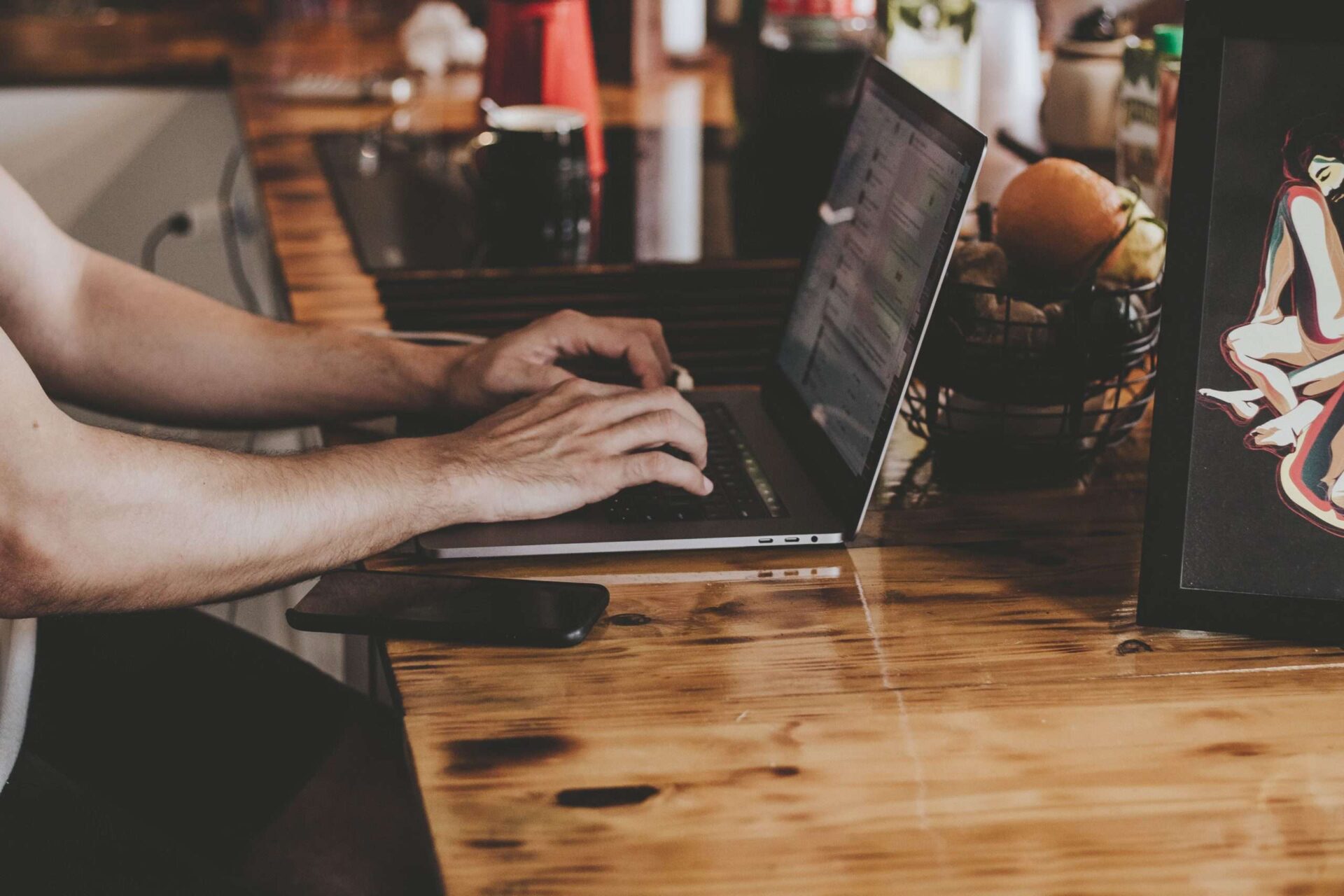 Person working on laptop with phone next to them at a desk