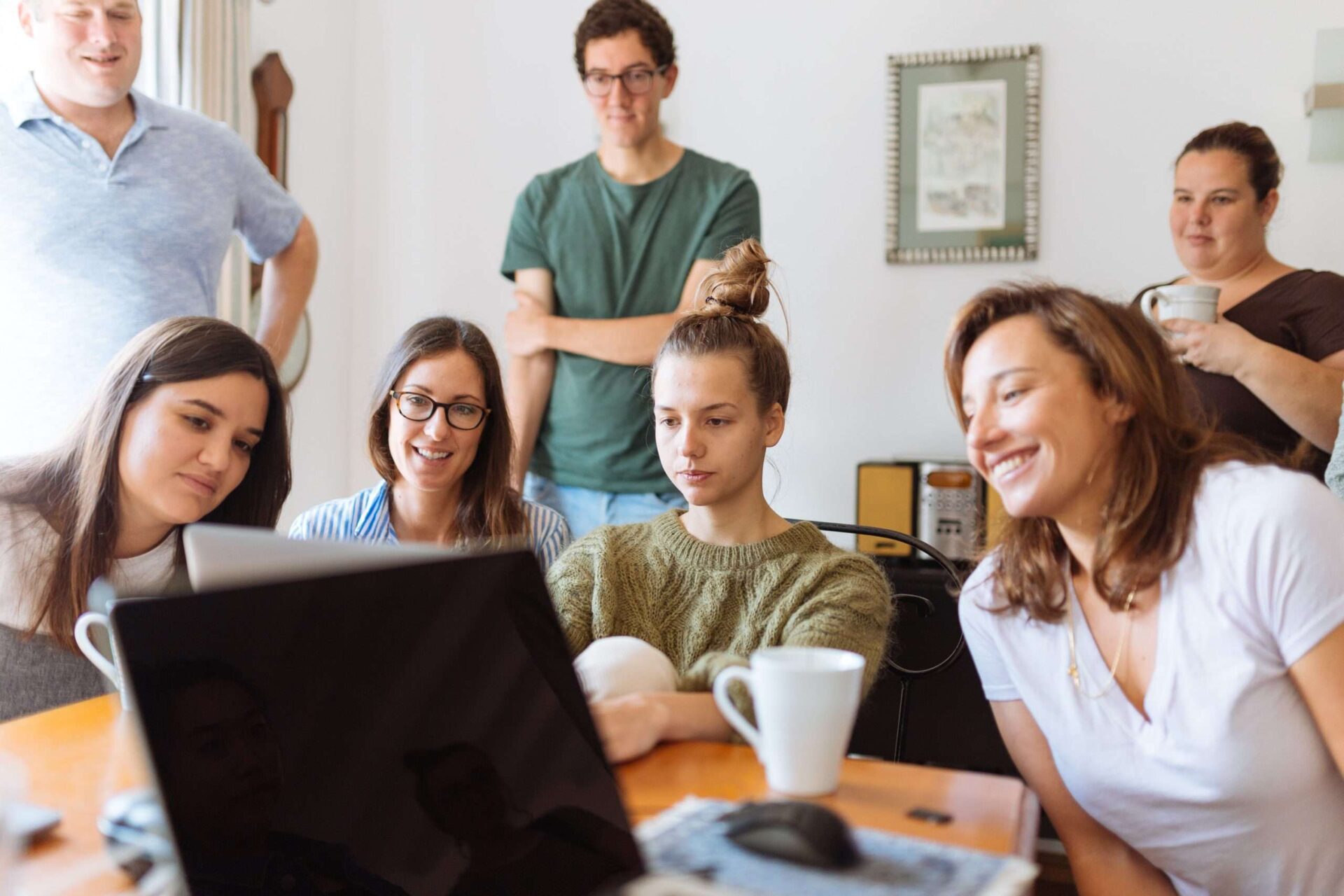 Group of smiling adults looking at a laptop screen