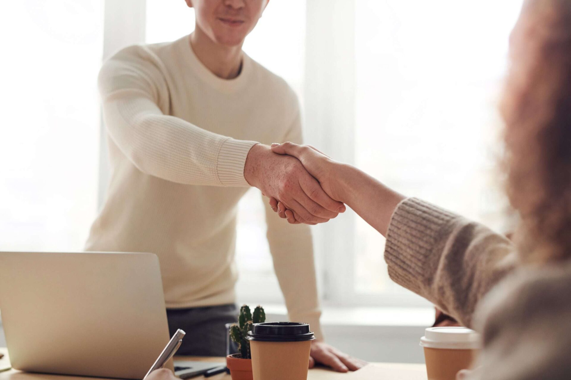 Man and woman shake hands across a desk