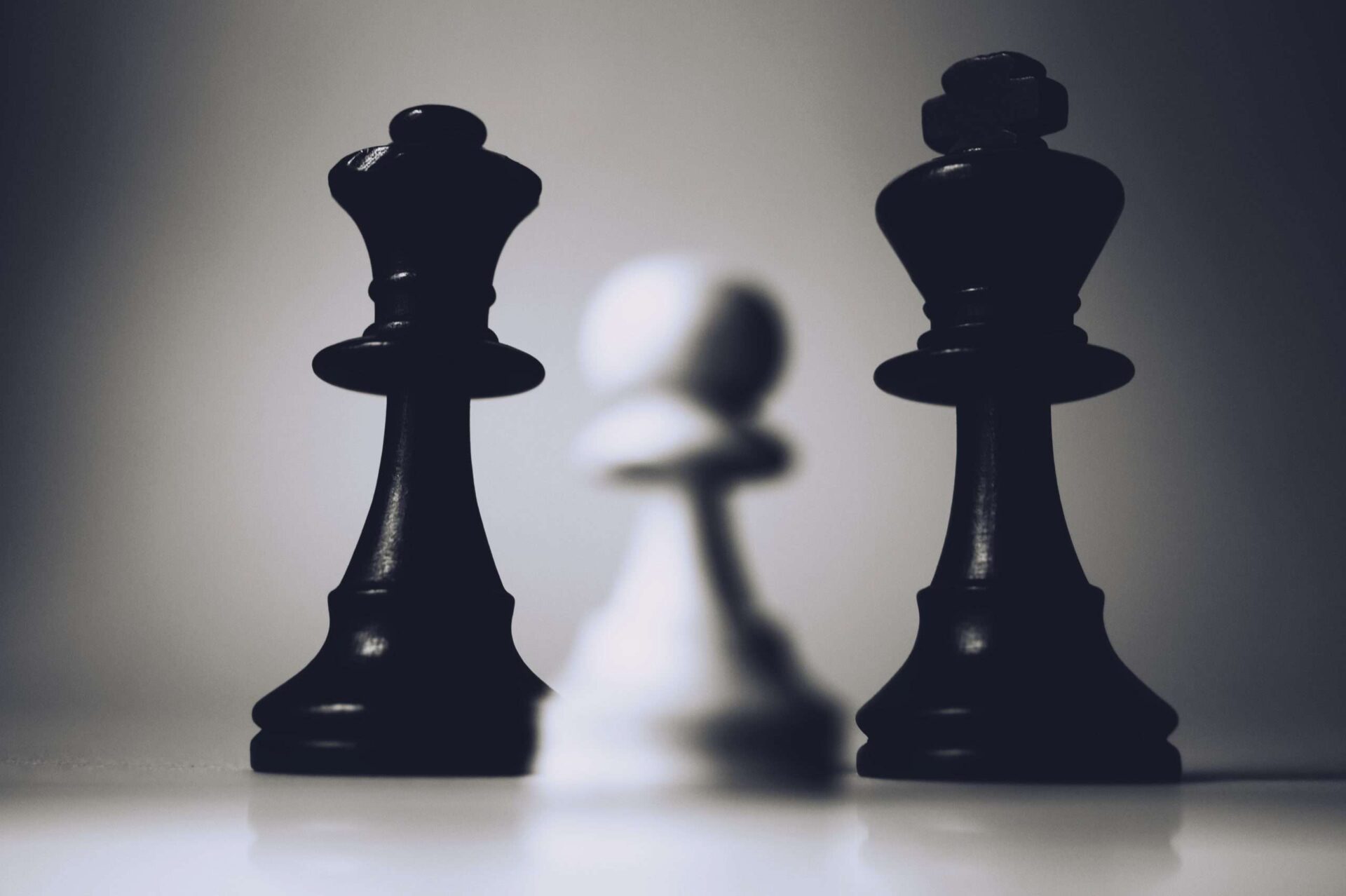 Close up of chess game with small white pawn against black king and queen