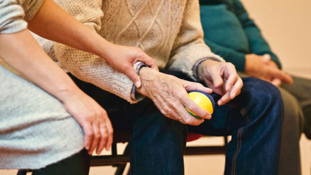 Care home worker holds the arm of an elderly man