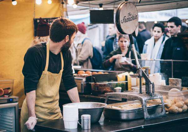 A small food business at a stall with a line of customers