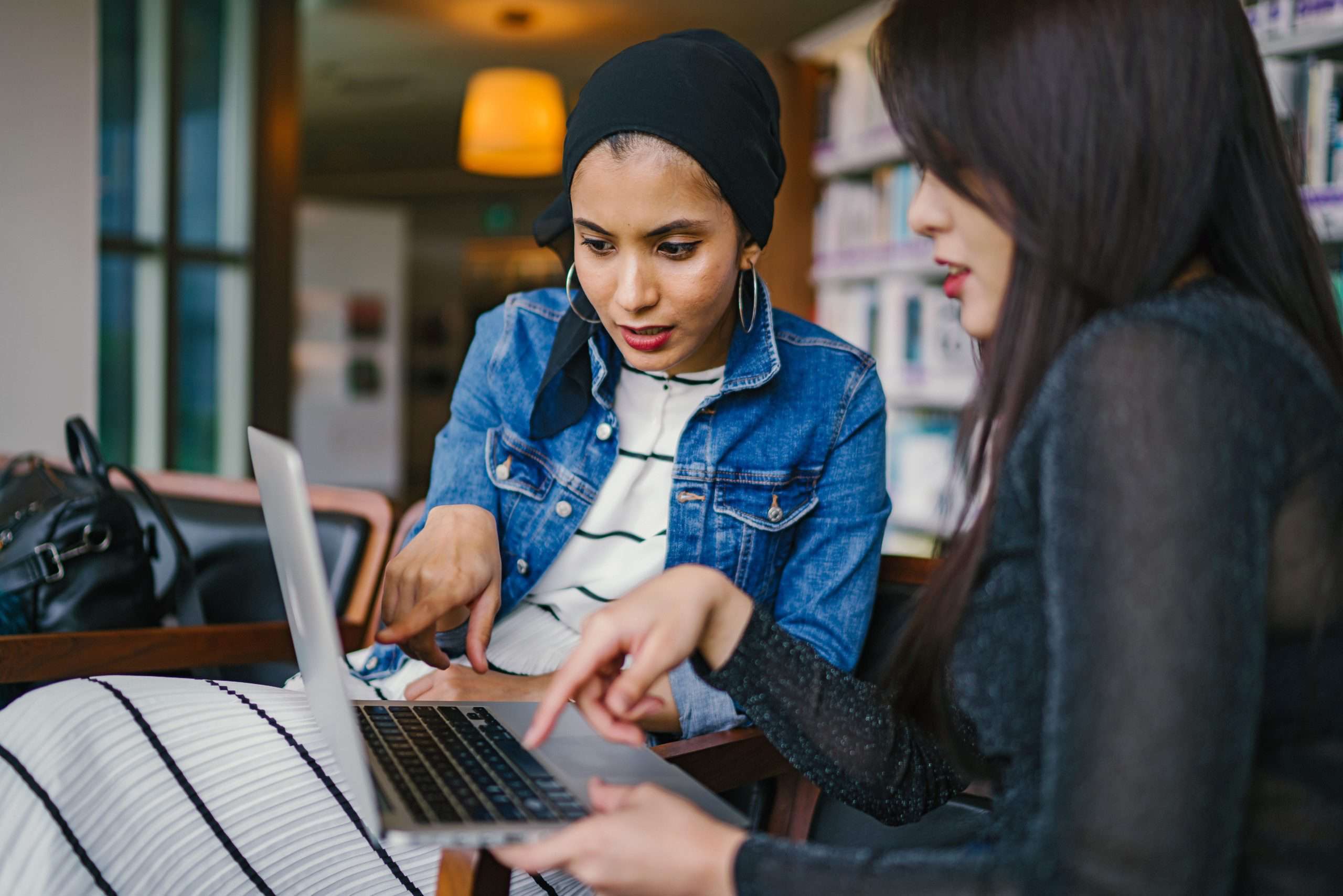 Two women using a laptop and pointing at what is on screen