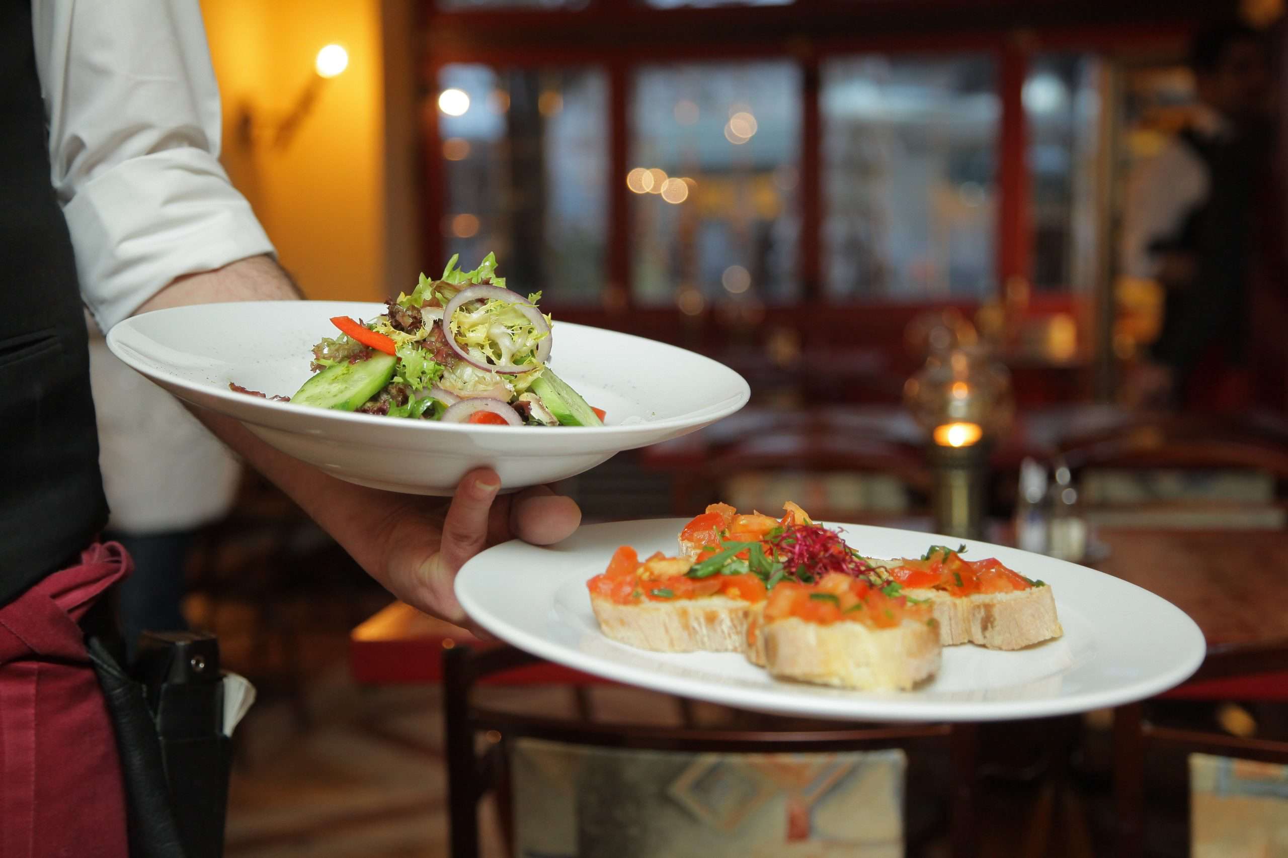 Close up of waiter serving two plates of fine food