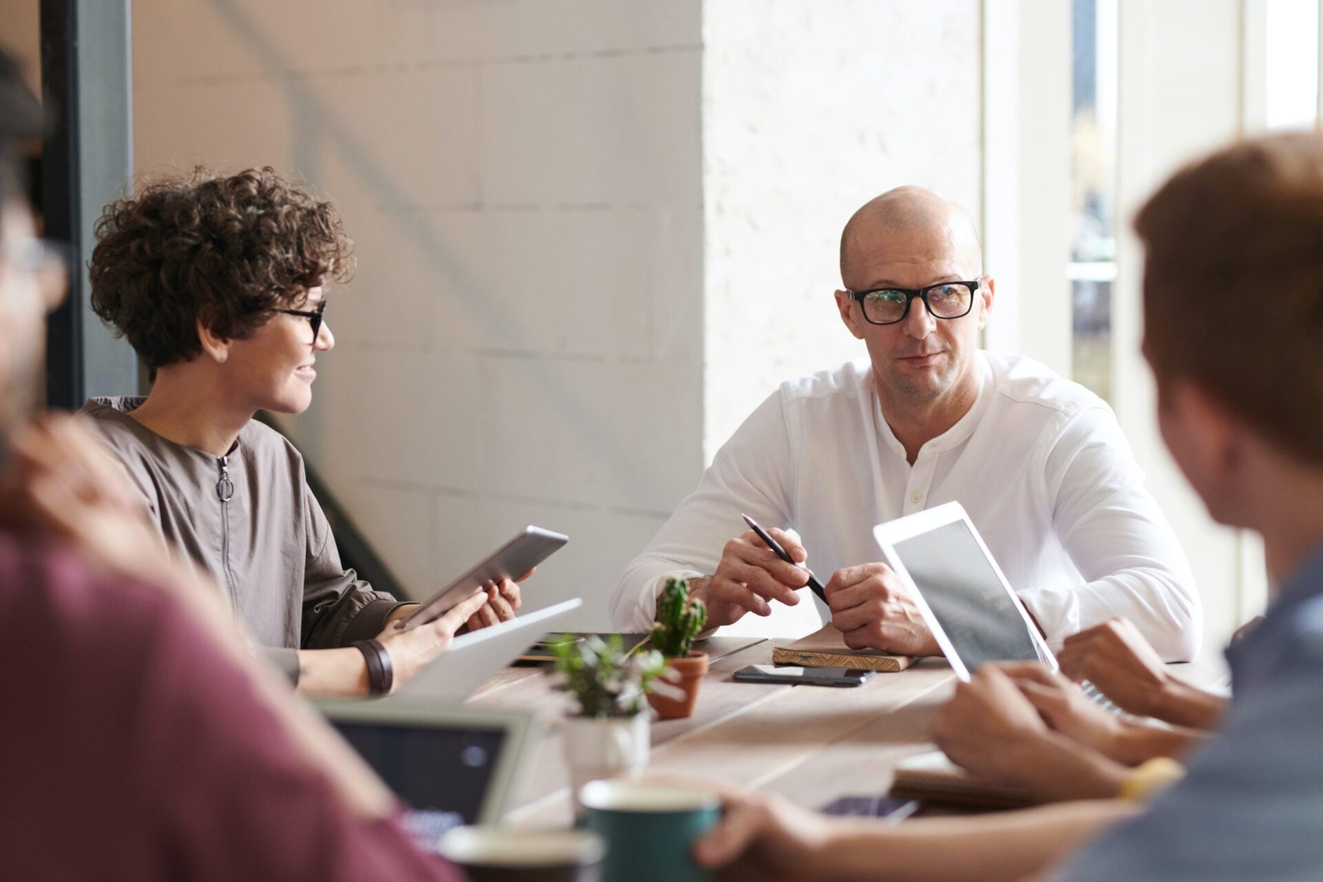 Business meeting around a table using tablets and laptops