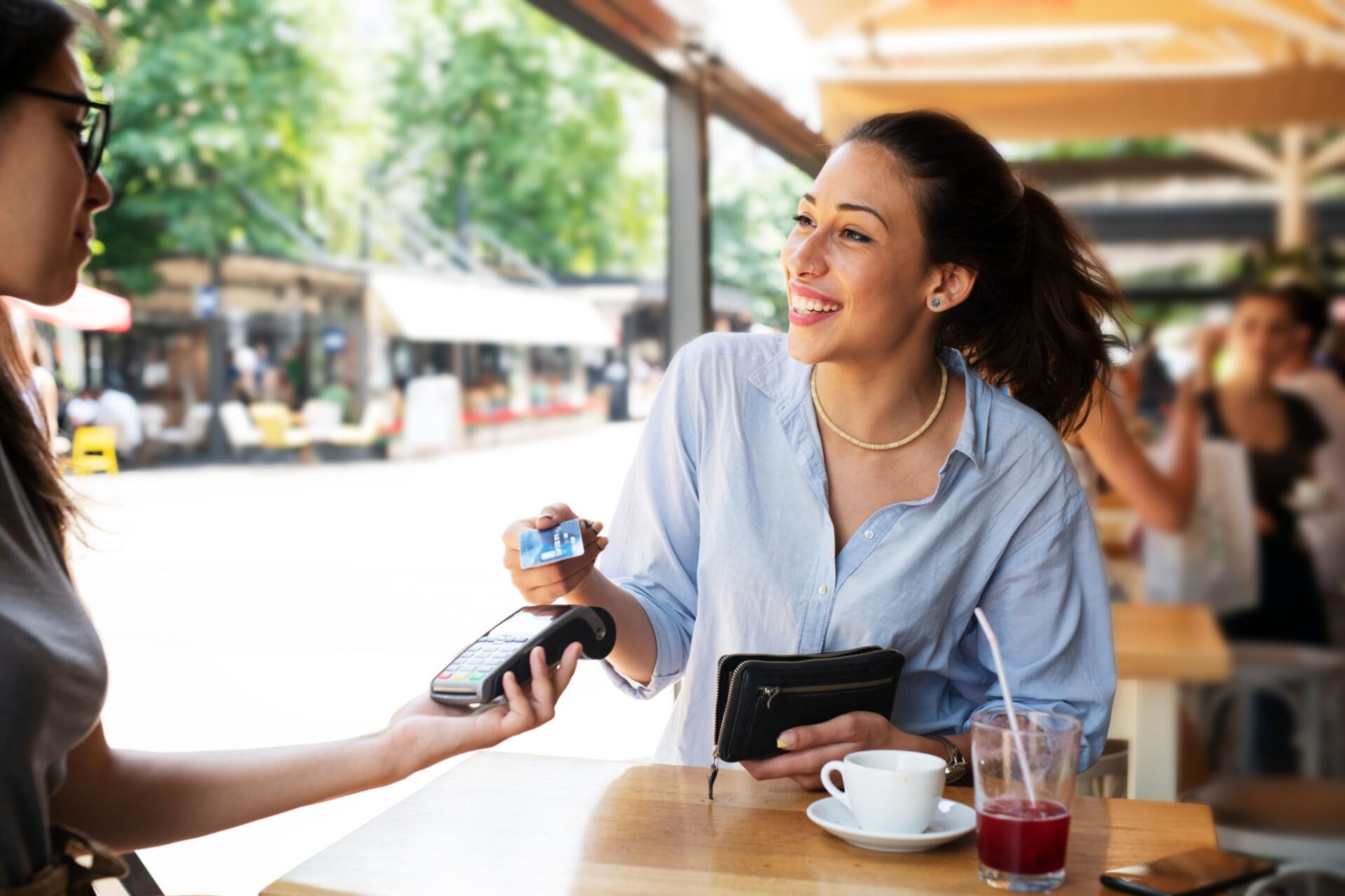 Smiling woman paying for a drink with a contactless card