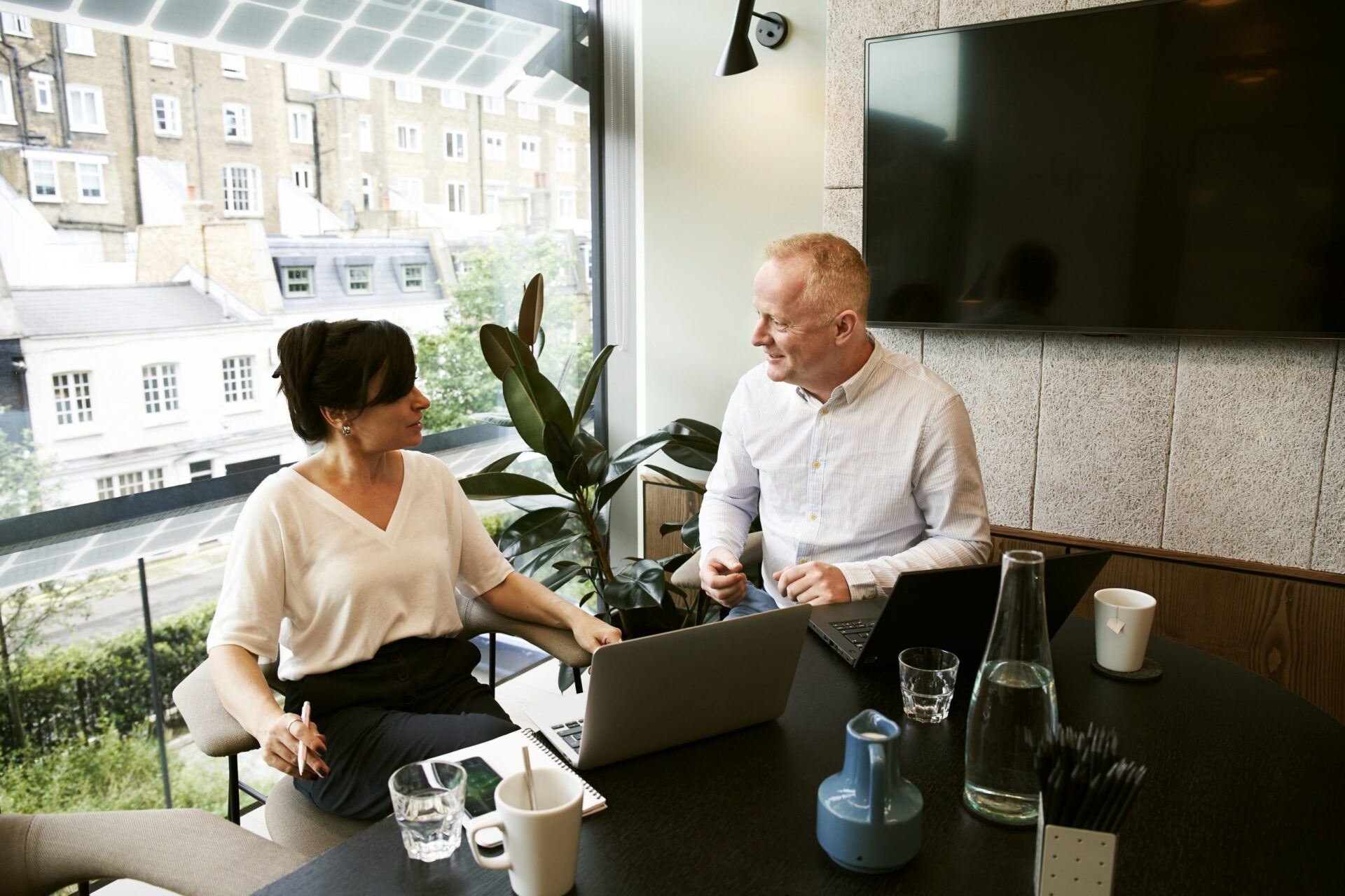 Man and woman talking as they work at their laptops