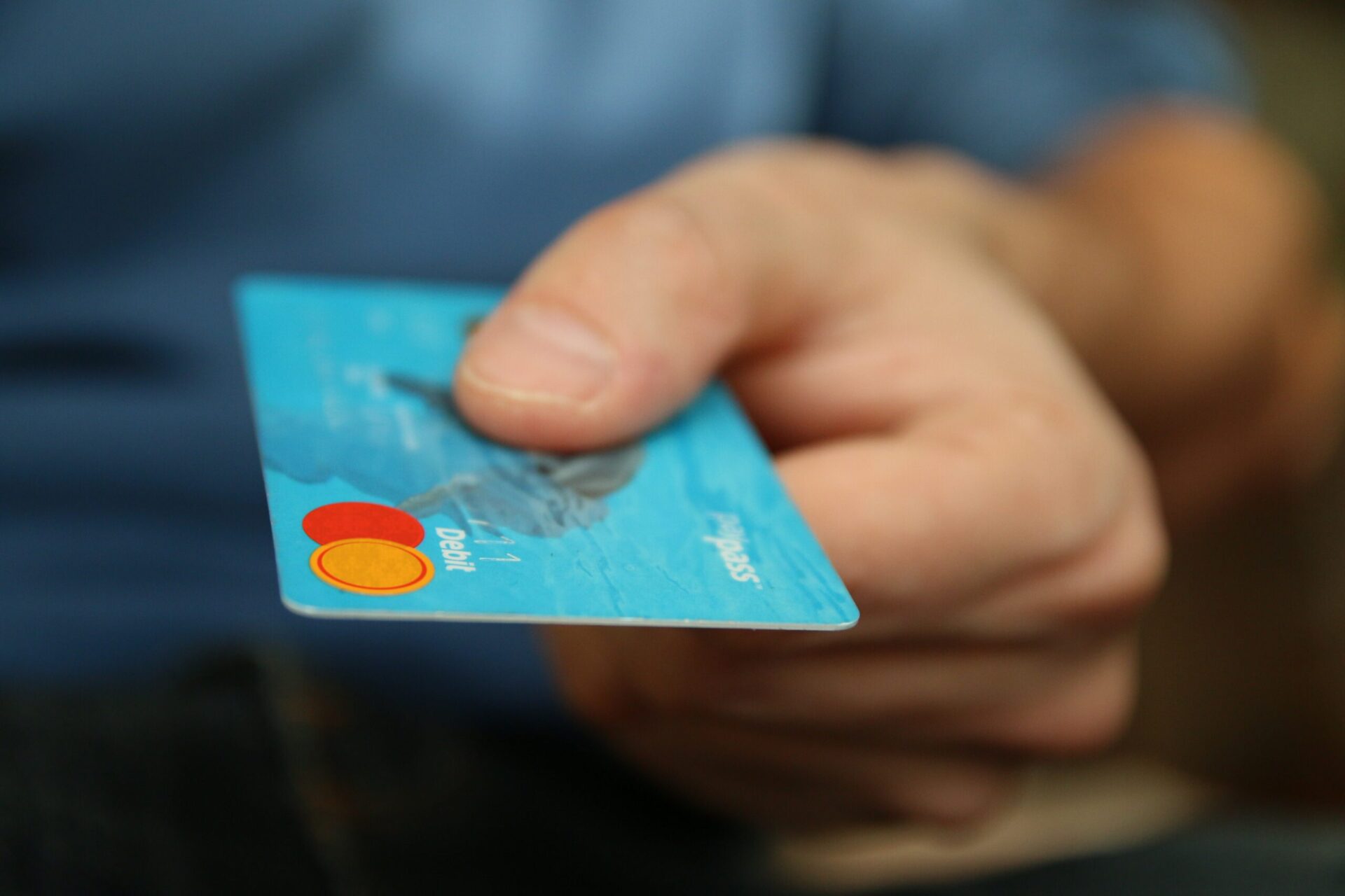 Closeup of a hand holding a debit card to a cashier