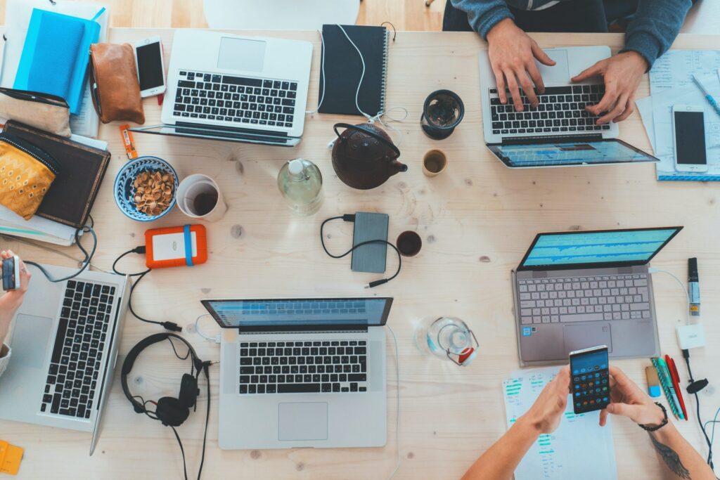 A top down view of people working on laptops around a table