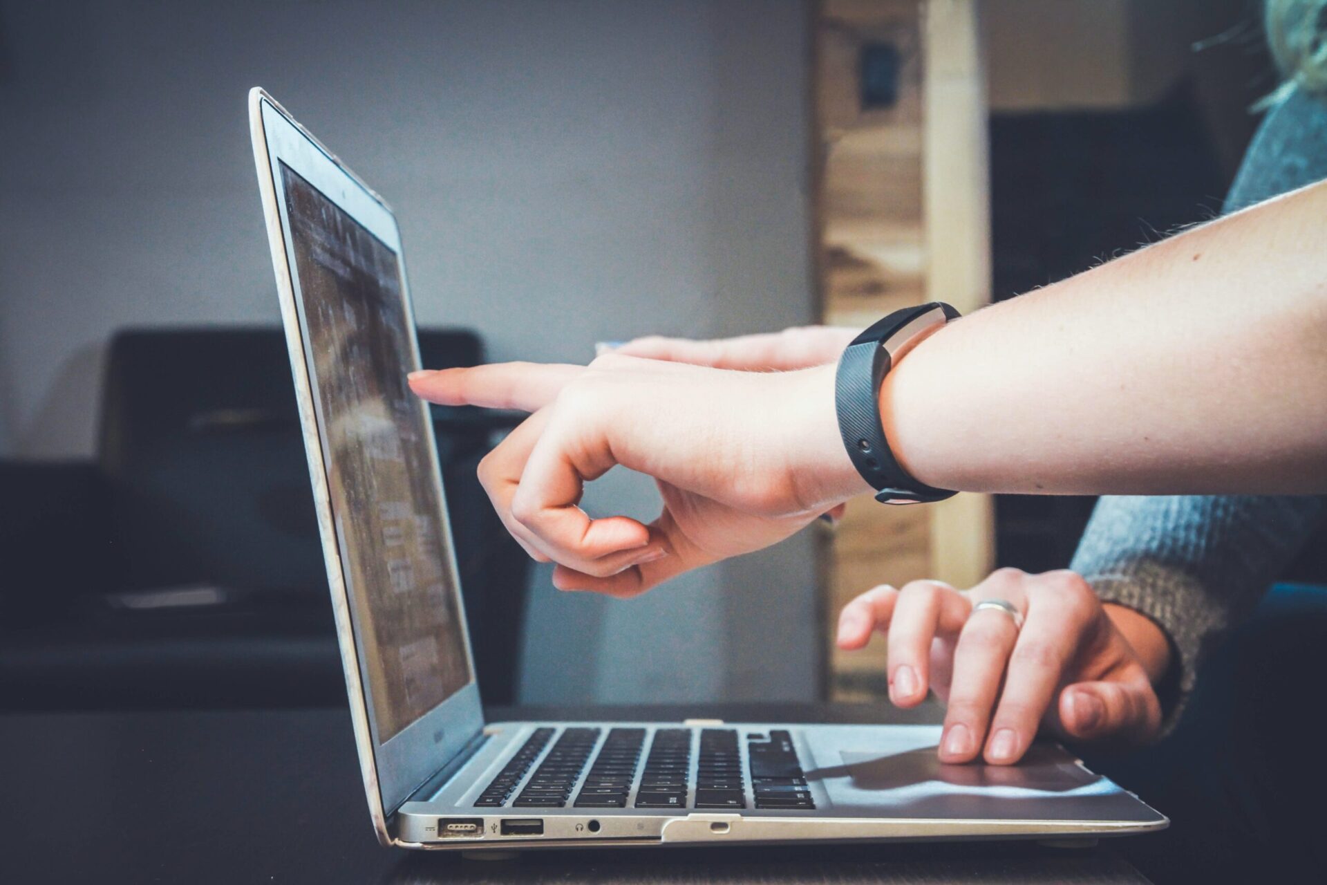 Close up of hands pointing at a laptop screen