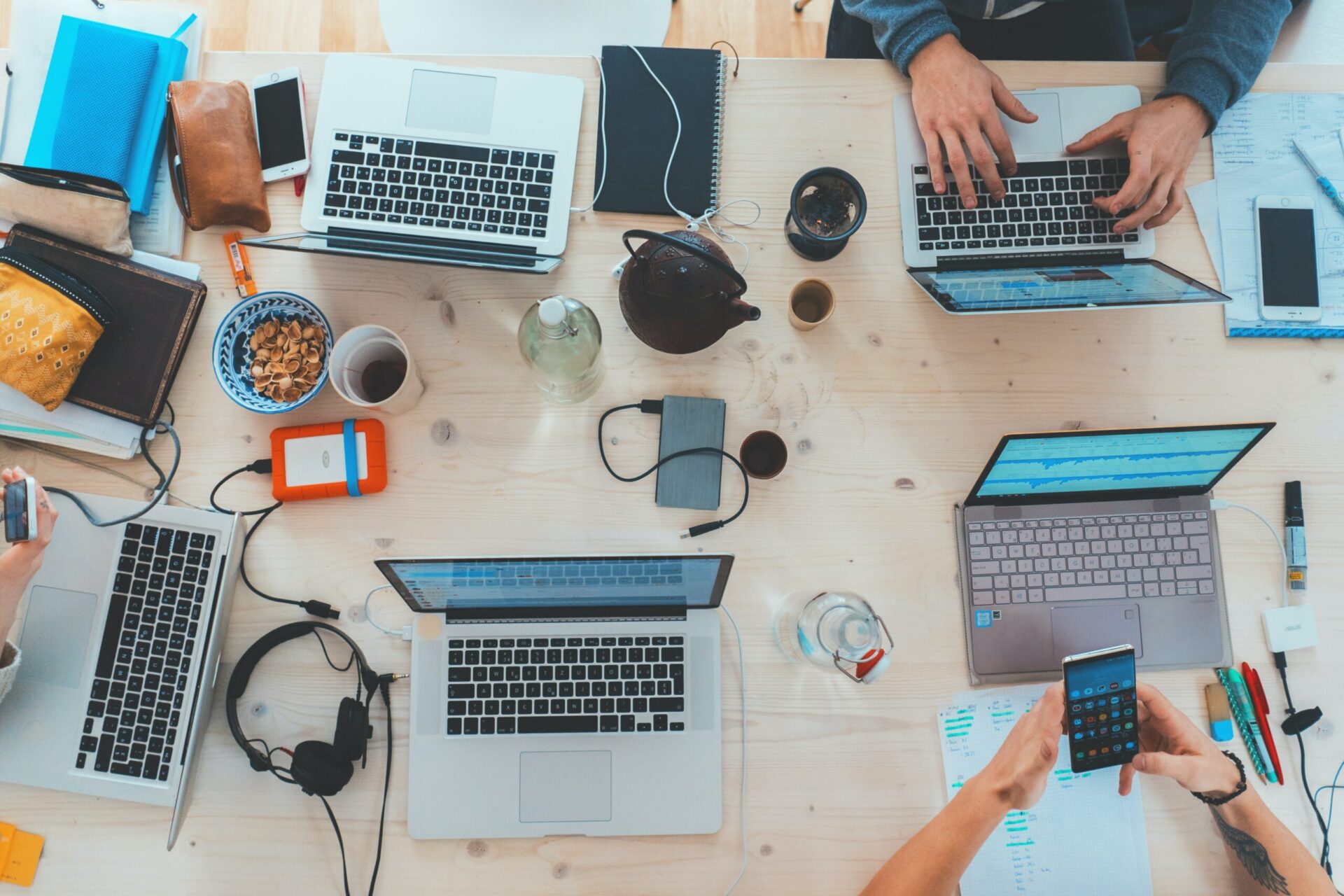 A top down view of people working on laptops around a table