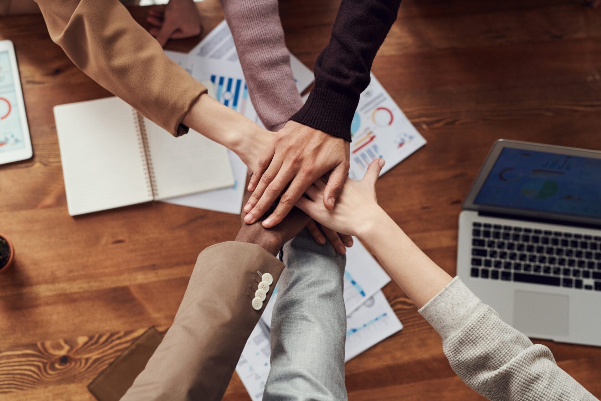 A team of six people putting their hands together to cheer
