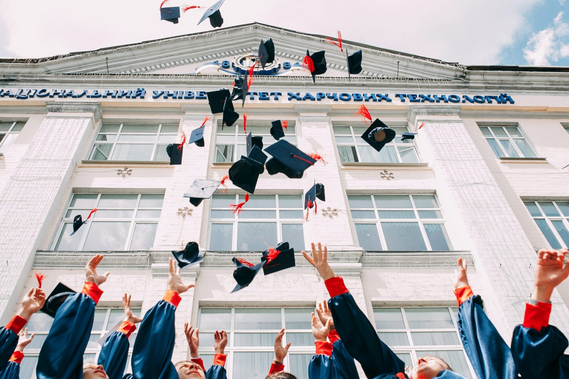 Low shot of a group of graduates throwing their caps in the air in celebration
