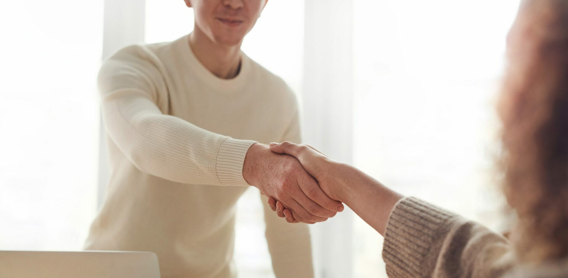Closeup of two people shaking hands across a desk