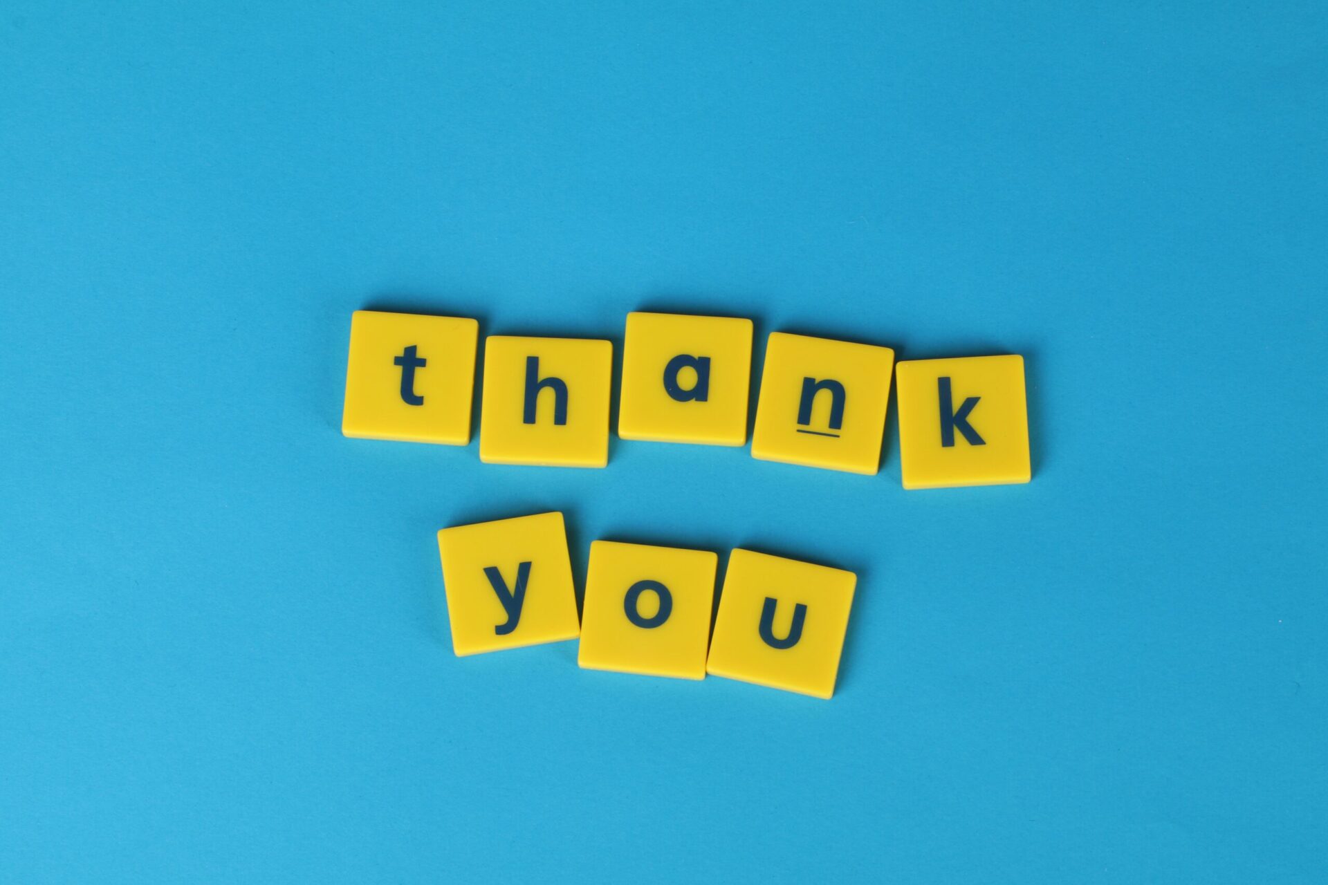 Thank you spelled out with yellow letter blocks on a blue background