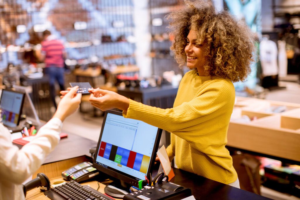 Happy female customer handing her credit card to a shop assistant in a store