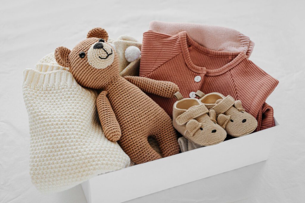 Box with baby stuff and accessories for a newborn baby, including a toy, shoes and a blanket
