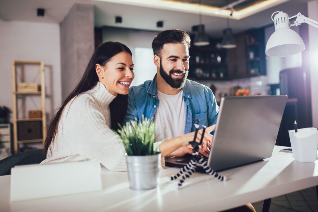 Happy couple doing business together working at home on the lapt