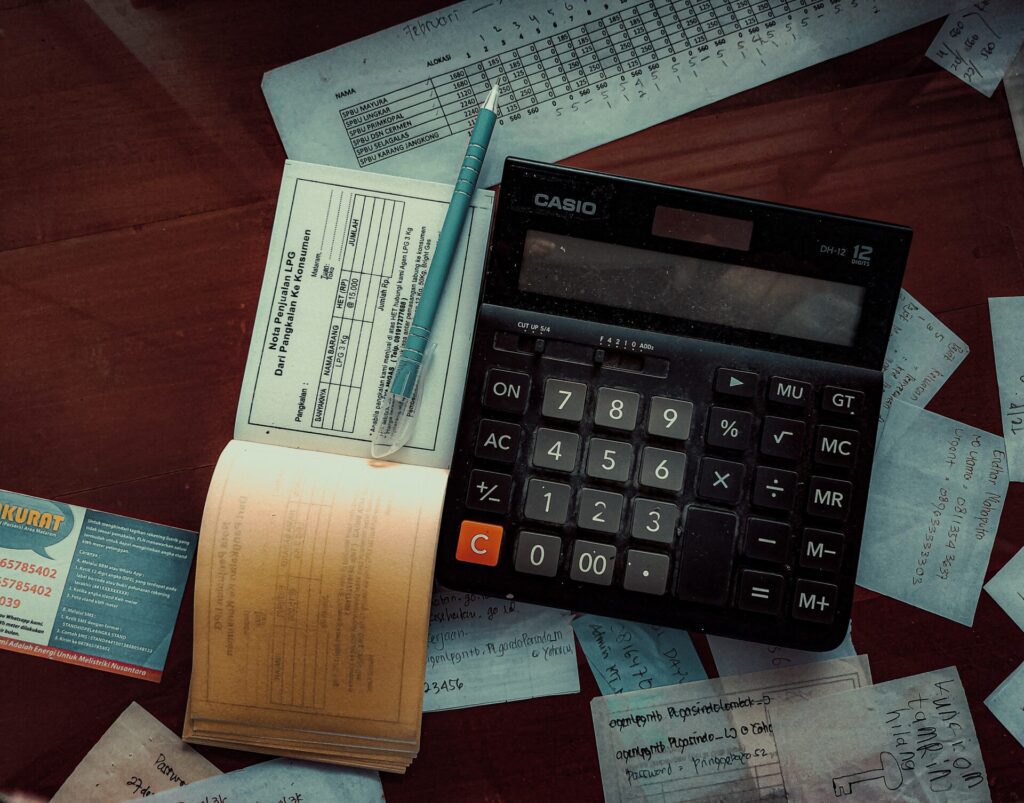 Top down view of a calculator and cheque book on a messy desk