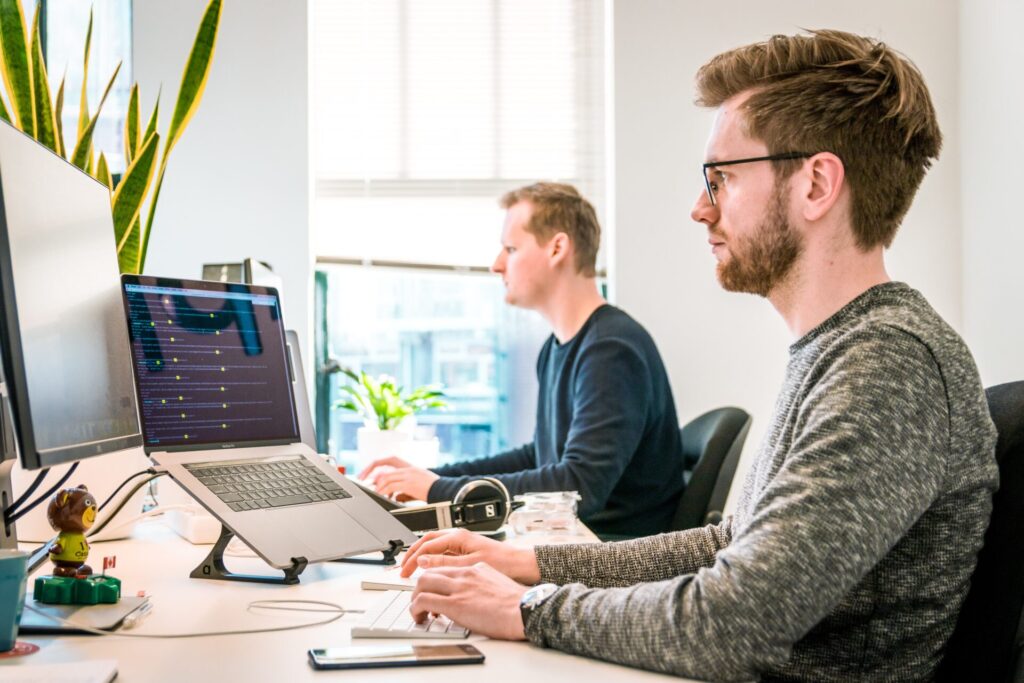 Two men working at computers in a clean bright office