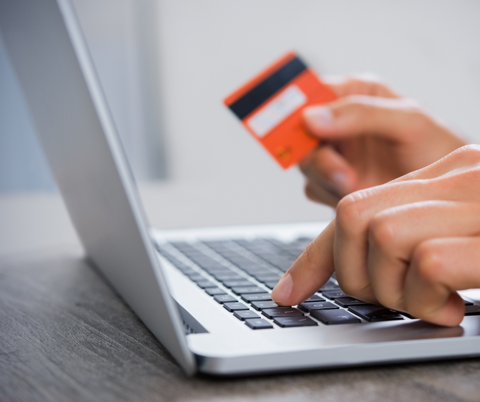 Closeup of someone holding a debit card and inputting the details on a laptop