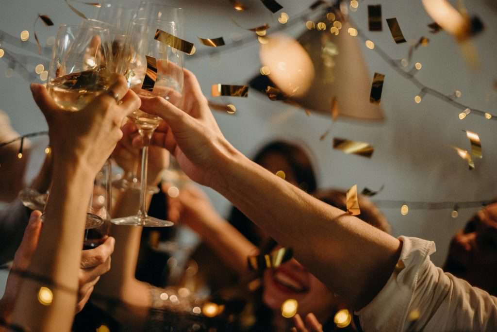 Close up of wine glasses clinking to celebrate as confetti falls