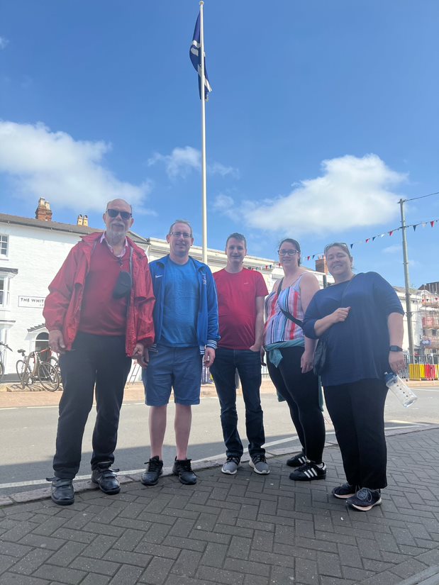 Solutions employees posing by a flag as part of a scavenger hunt