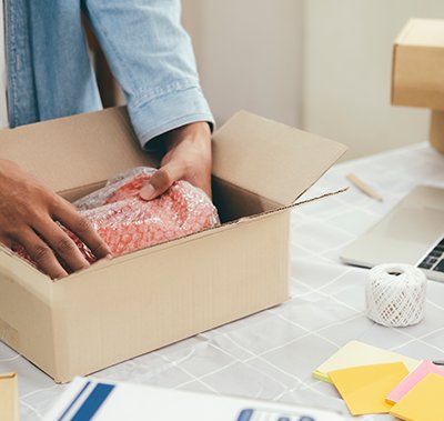 Person putting a product wrapped in bubble wrap into a box
