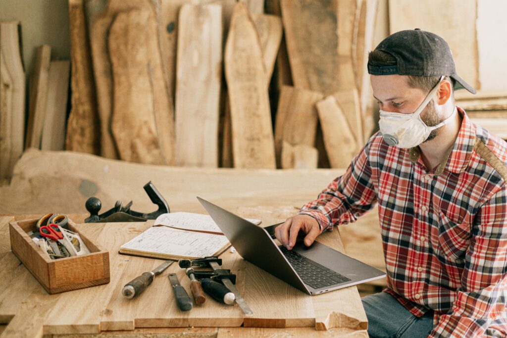 Man in a carpentry workshop working at a laptop