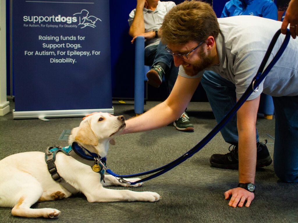 Solutions employee Adam petting a dog at Support Dogs