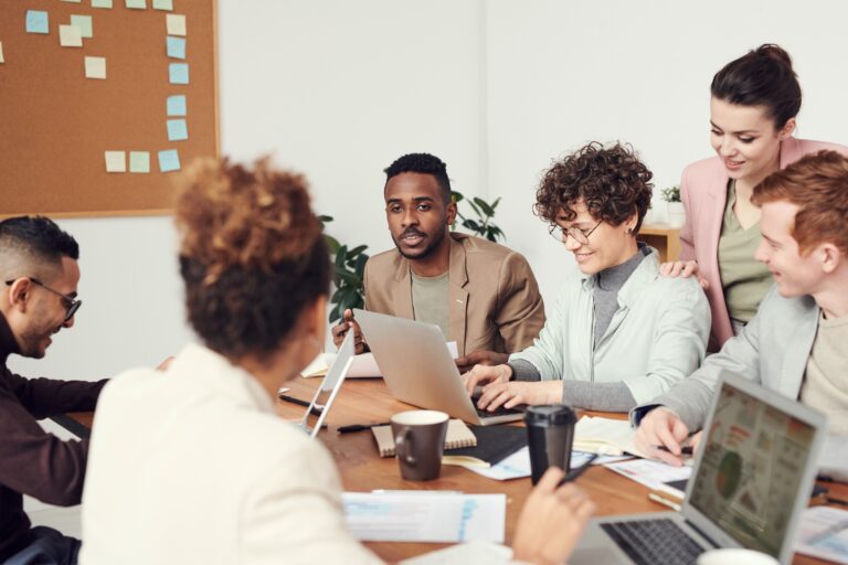 Collection of young business people around a table having a meeting and working at laptops