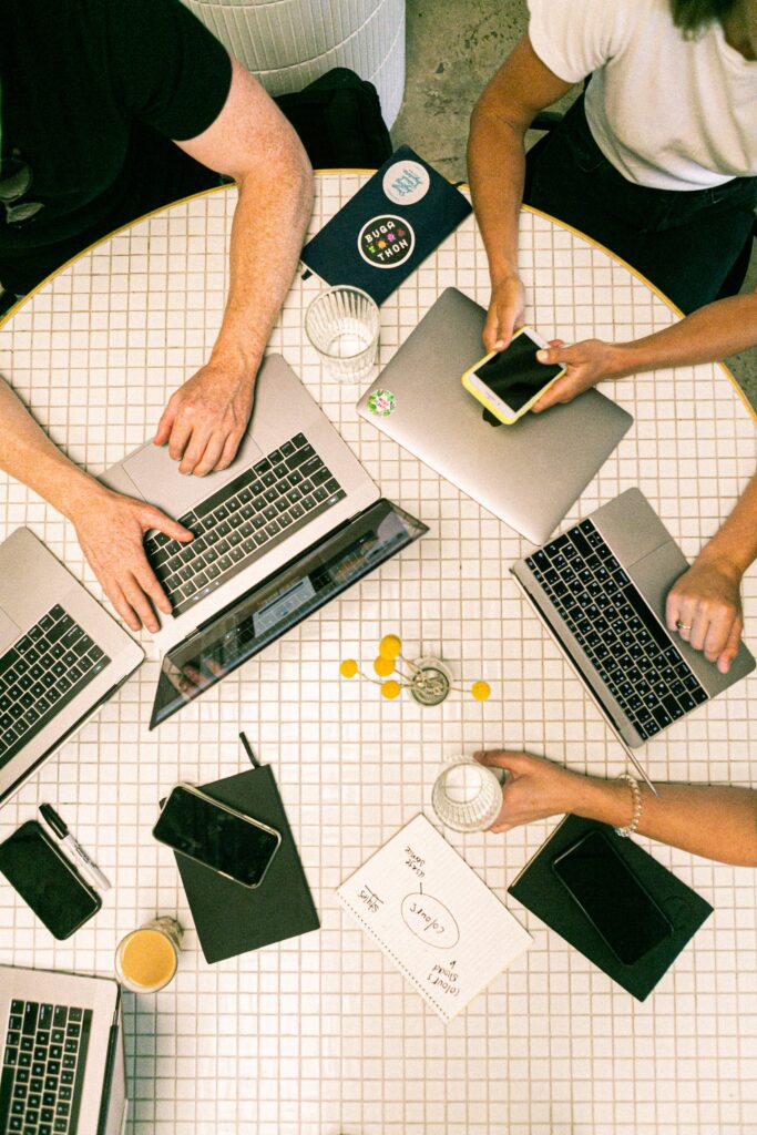 Top down view of several people working at laptops around a small circular table
