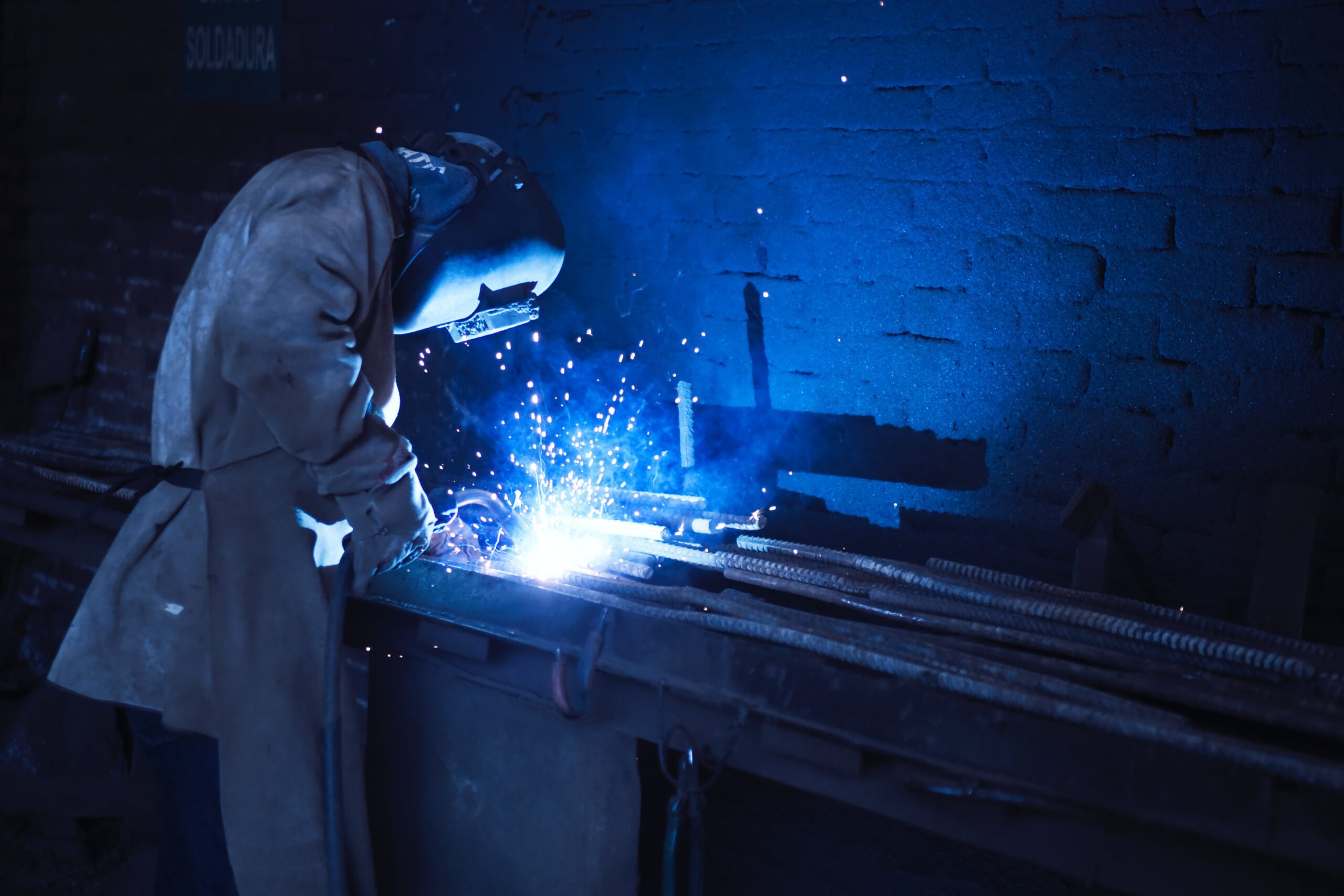 Photo with a blue tint of a person welding in a factory