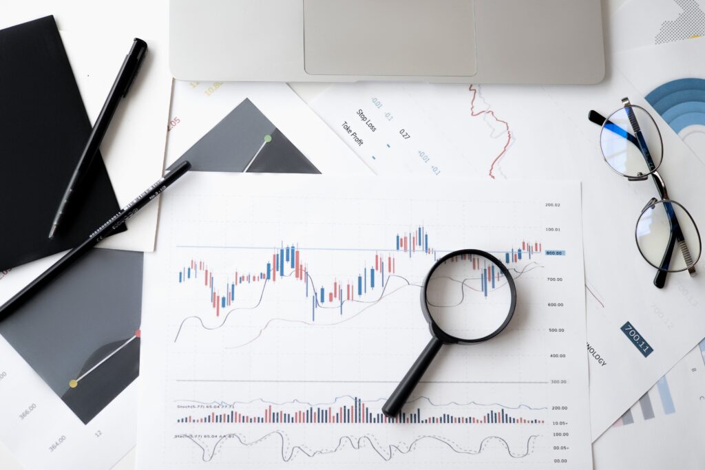 magnifying glass laying atop documents showing graphs and data