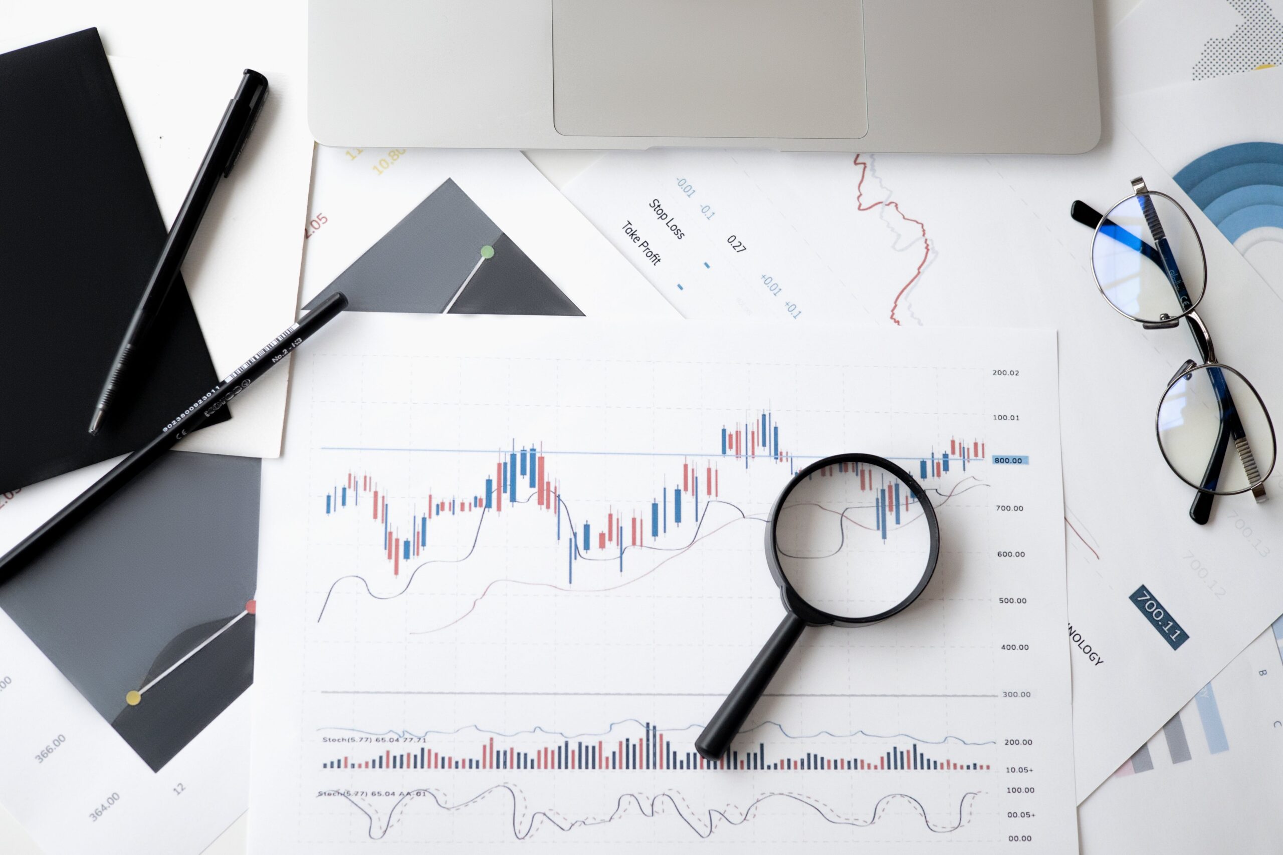 magnifying glass laying atop documents showing graphs and data