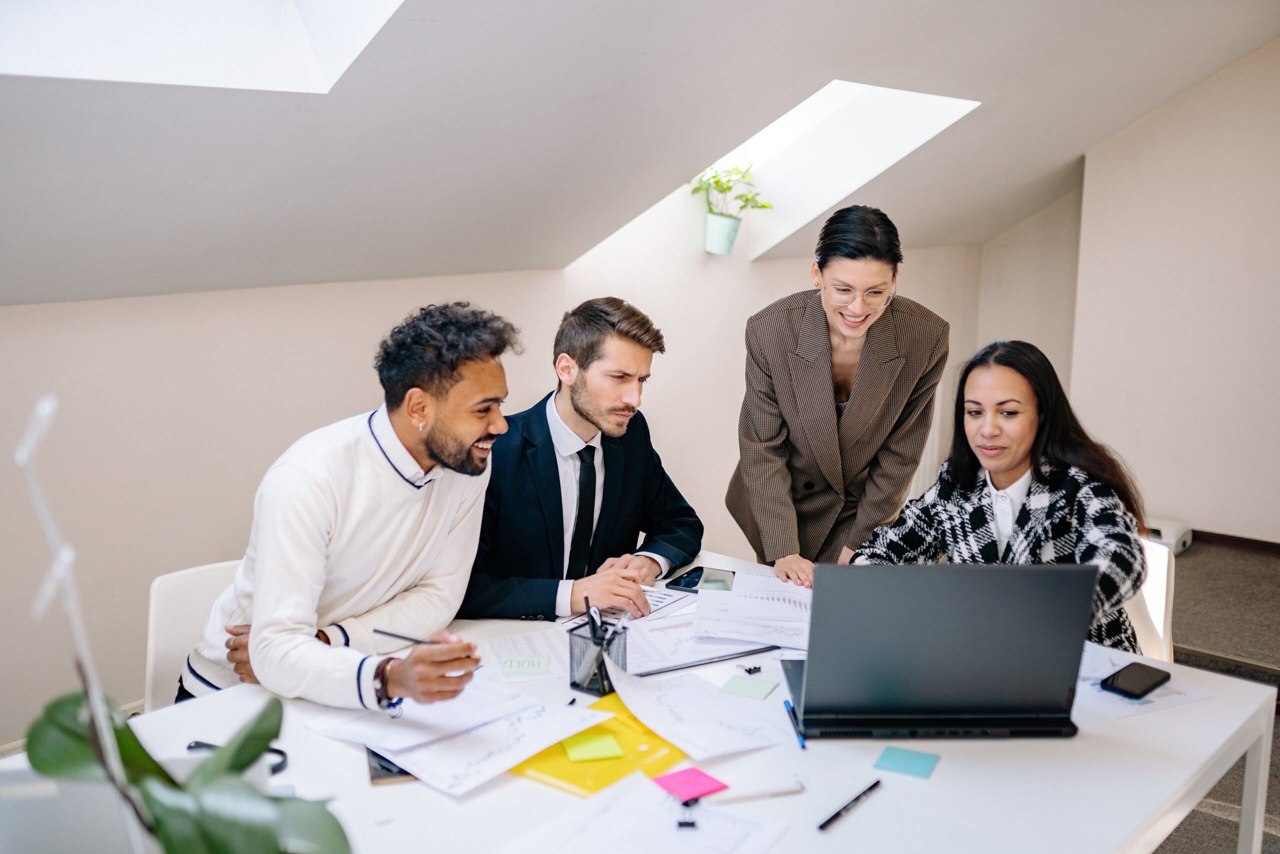 Business team sat around a table with a laptop and business papers
