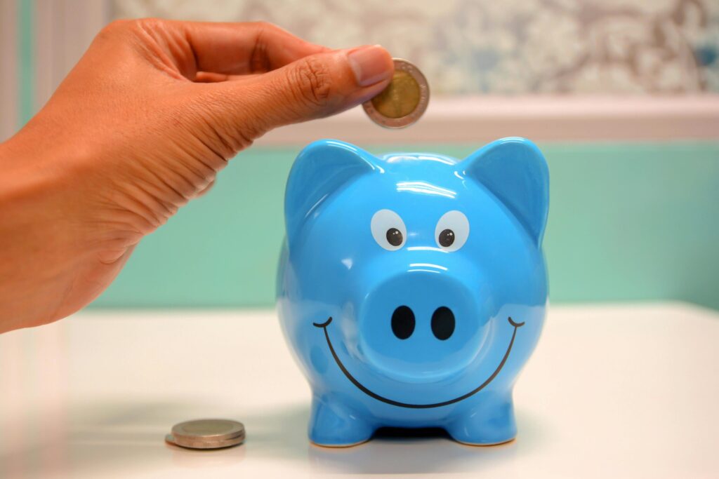 Closeup of a hand putting a coin into a blue piggy bank