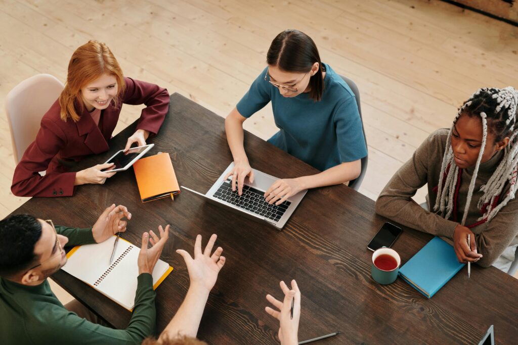 Several young business people meeting around a table with laptops and notebooks