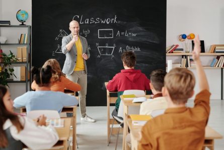 School classroom with a blackboard as teacher calling on a student who has raised their hand