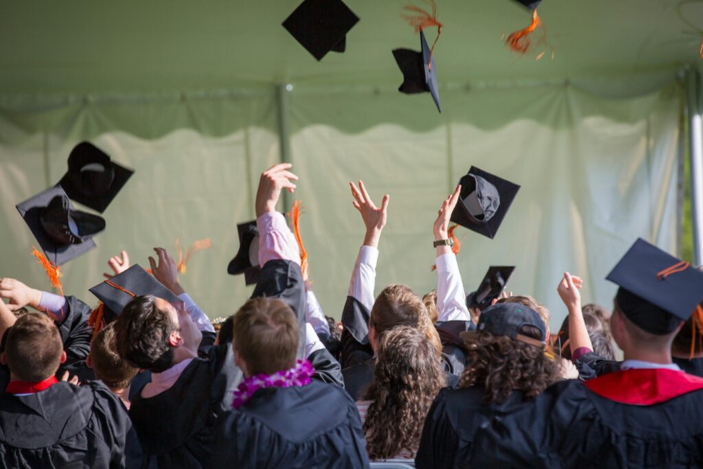 Photo of students celebrating graduation by throwing their caps in the air