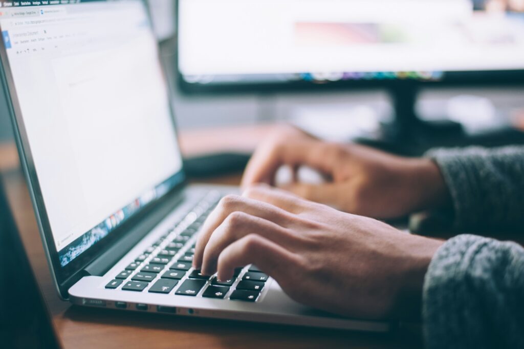 Closeup photo of a persons hands typing at a laptop