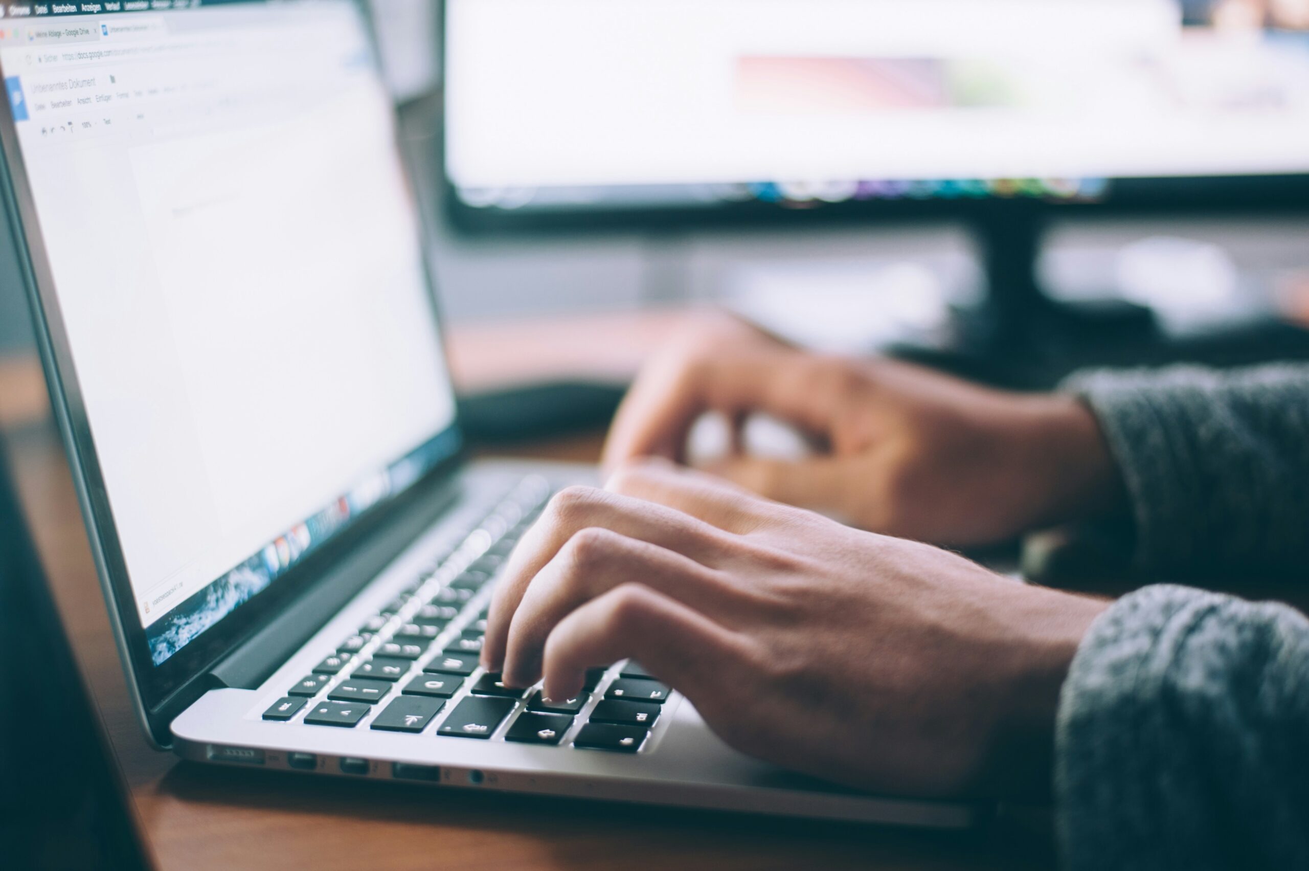Closeup photo of a persons hands typing at a laptop