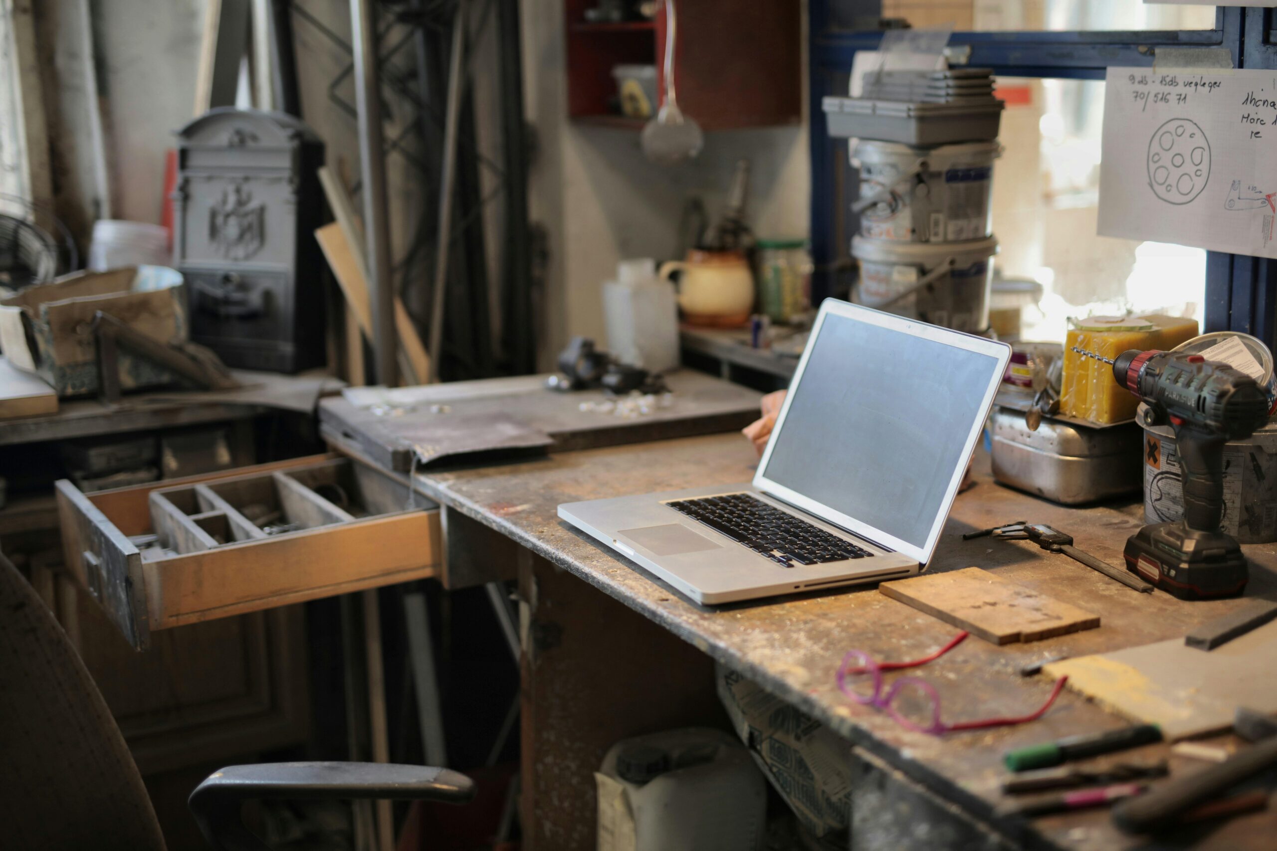 Laptop on a workbench surrounded by powertools and miscellaneous supplies